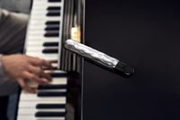 RELX Artisan Device Silver Wave lying on top of Piano